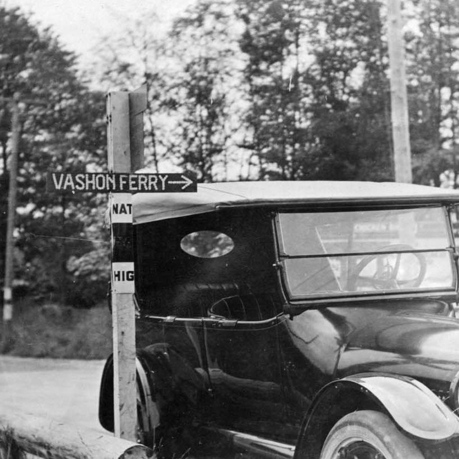 Black car parked next to a sign for Vashon Ferry
