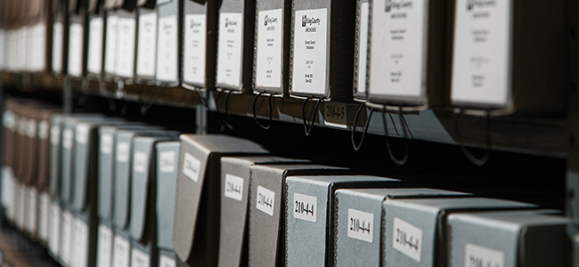 Grey boxes lining a large bookshelf